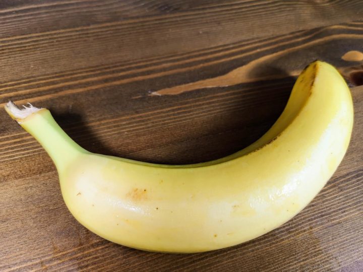 Eine Banane mit Schale auf einem Holztisch